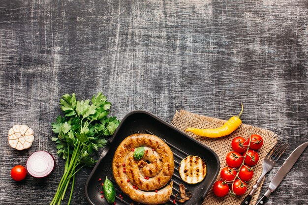 Fresh tasty ingredient and fried snail sausages at bottom of the grey wooden textured