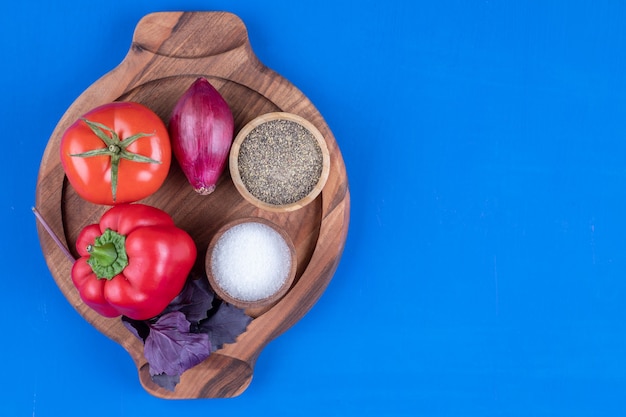 Fresh tomato, onion and red bell pepper on wooden board.