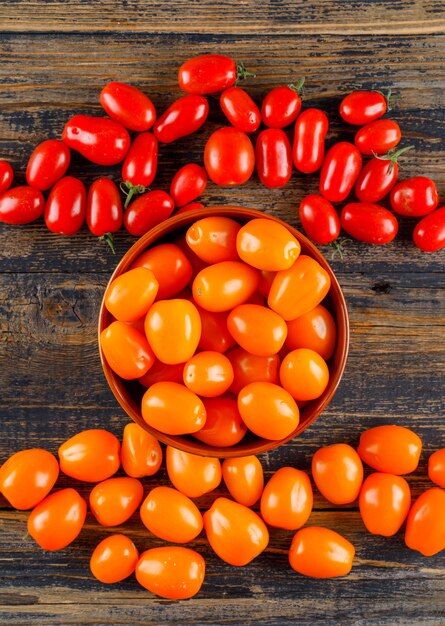 Fresh tomatoes in a bowl on a wooden table. flat lay.