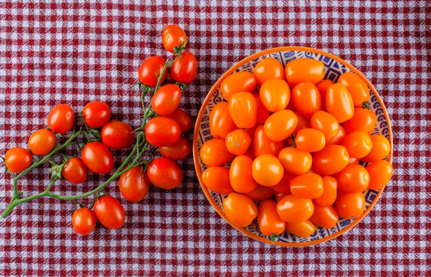 Fresh tomatoes in a plate on a picnic cloth. flat lay.