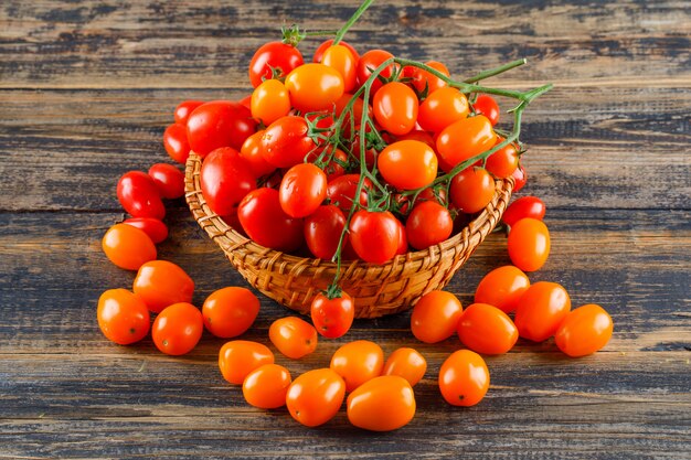 Fresh tomatoes in a wicker basket on a wooden table.