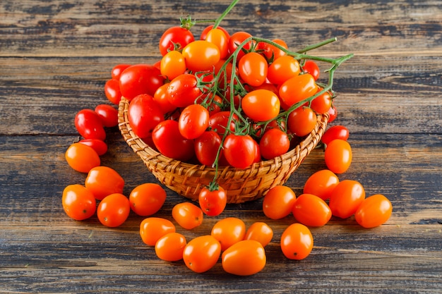 Fresh tomatoes in a wicker basket on a wooden table.