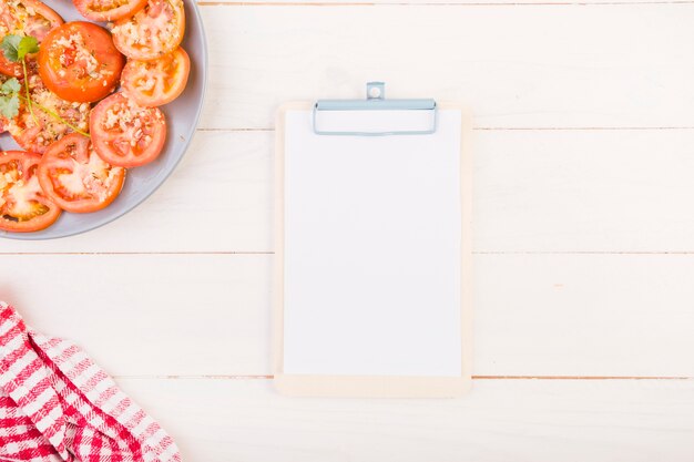 Free photo fresh tomatoes with clipboard on kitchen table