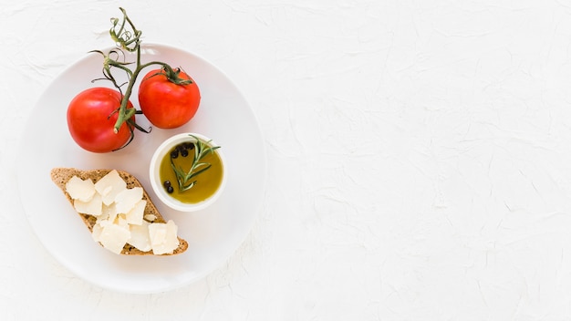 Foto gratuita pomodori freschi con olio d'oliva e pane sani vergini su fondo bianco