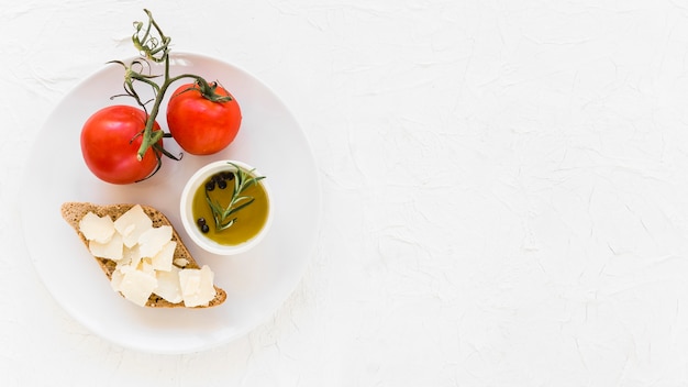 Fresh tomatoes with virgin healthy olive oil and bread on white background