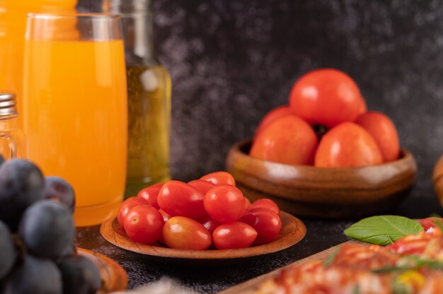 Свежие помидоры в деревянной чашке, виноград и апельсиновый сок в стакане.