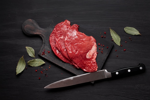 Fresh uncooked meat on wooden board with knife