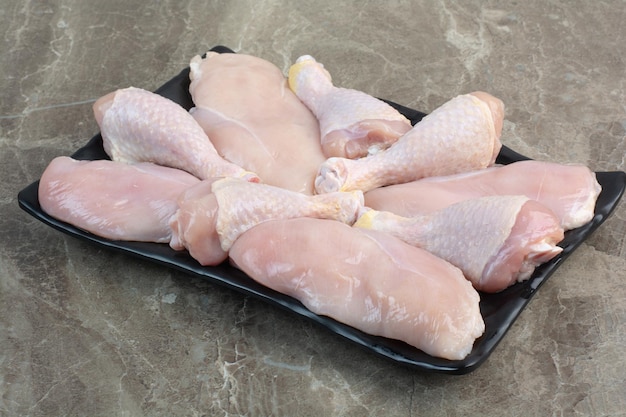 어두운 접시에 신선한 준비되지 않은 닭 다리. 고품질 사진