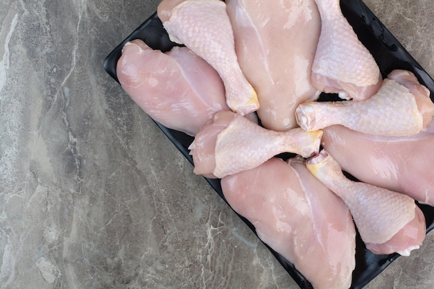 어두운 접시에 신선한 준비되지 않은 닭 다리. 고품질 사진