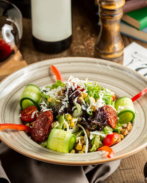 Fresh vegetable salad with cucumber, lettuce, dried tomatoes, corn and walut