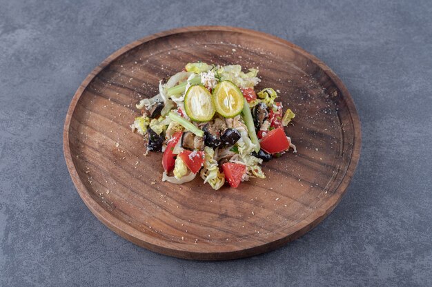 Салат из свежих овощей на деревянной тарелке.