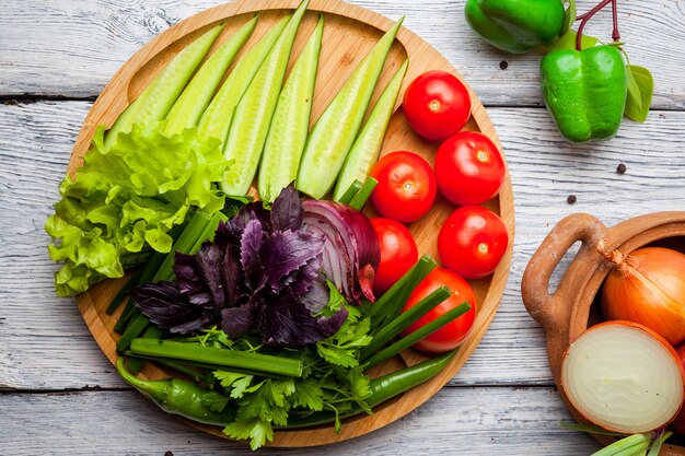 Fresh vegetables cucumber, tomato, onion, pepper on wooden cutting board