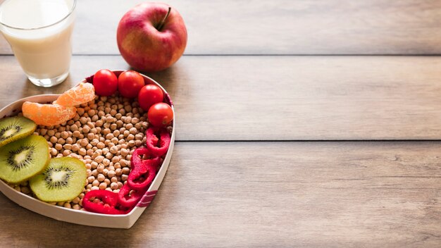 Fresh vegetables and fruits with glass of a milk on wooden background