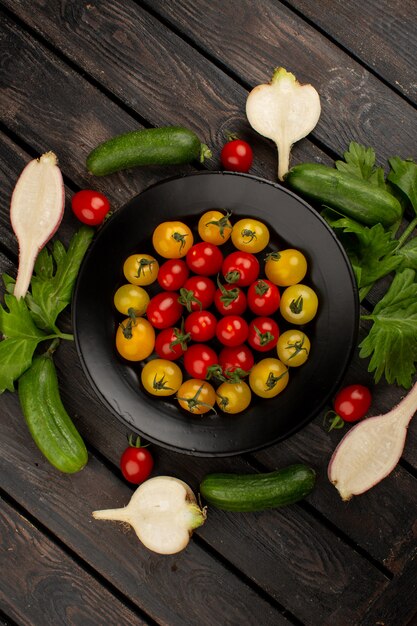 Свежие овощи спелые огурцы красные и желтые помидоры и редис на деревянном