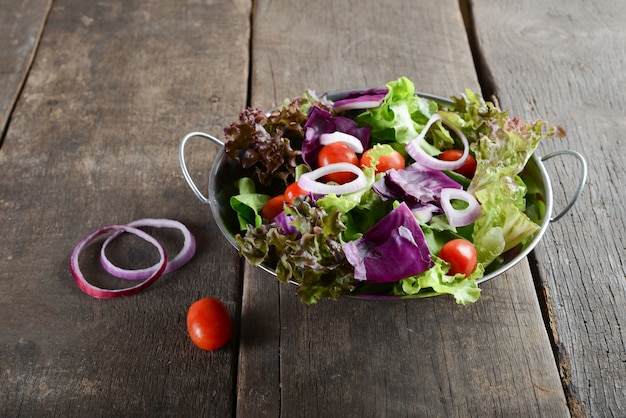 fresh vegetables salad in the bowl with rustic old wooden background.