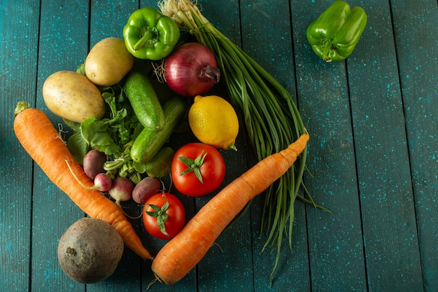 Fresh vegetables a top view of ripe vitamine riched salad like orange carrott potato red tomatoes and others on the green rustic surface