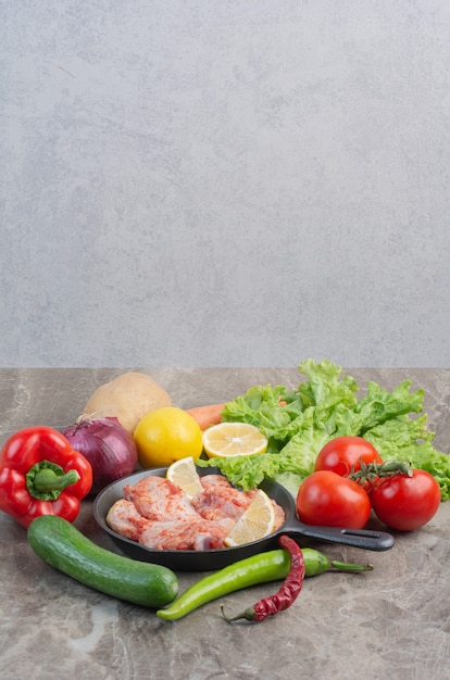 Fresh vegetables with raw chicken on marble background 