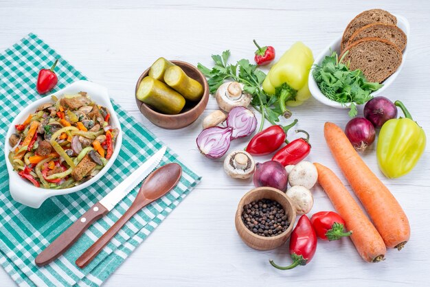 свежие овощи с нарезанным мясным блюдом и буханками хлеба на светлом столе, овощная еда, мясо