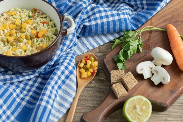 Fresh vegetables on wooden board with noodles