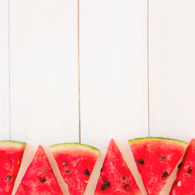 Free photo fresh watermelon slices in triangular shape on wooden plank