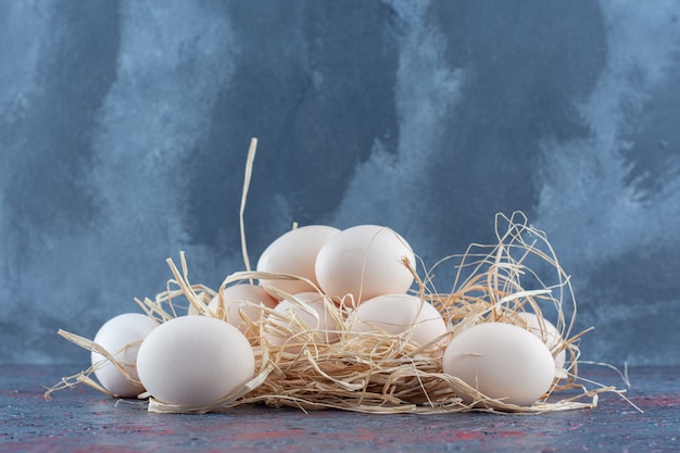 Fresh white and brown chicken eggs with hay .