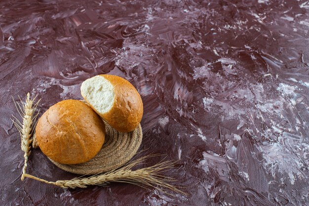 Fresh white buns with wheat ears on a light surface 