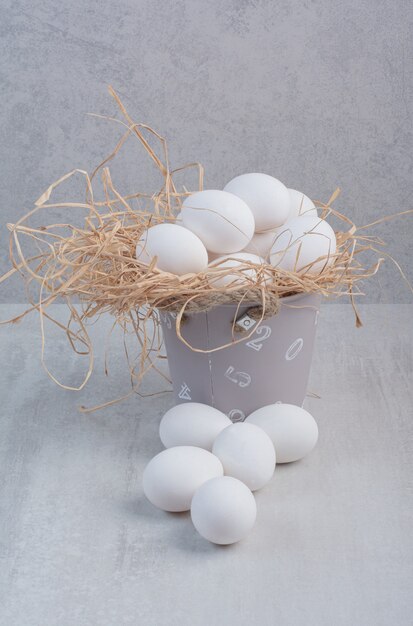 Fresh white eggs in bucket on marble background. 