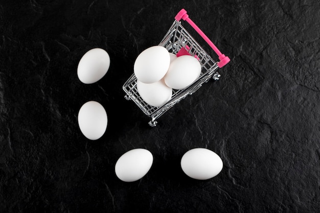 小さなショッピングカートに入った新鮮な白い卵。