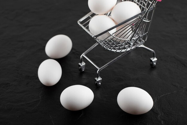 Fresh white eggs in small shopping cart. 