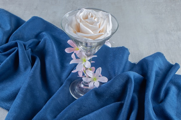 Free photo fresh white flowers in a glass on a piece of fabric, on the white table.