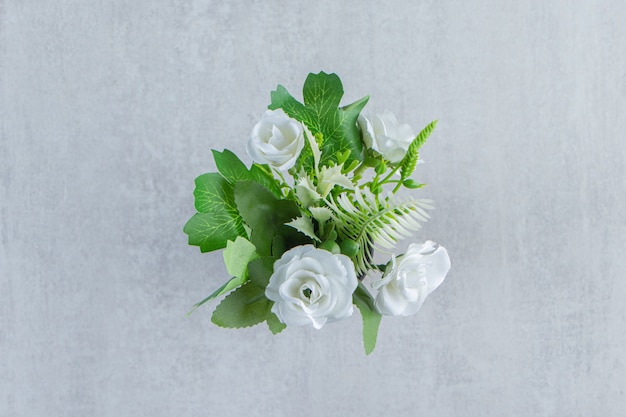 Fiori bianchi freschi in una brocca di legno, sul tavolo bianco.