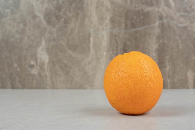 Fresh whole orange on gray table