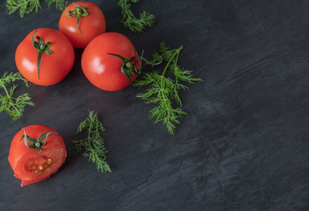 어두운 배경에 채소가 있는 신선한 전체 토마토.
