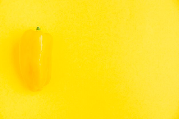 Fresh yellow bell pepper on yellow surface