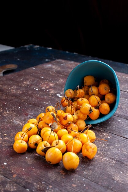 свежая желтая вишня, спелая и сочная на синей тарелке на коричневом деревянном, свежие спелые фрукты