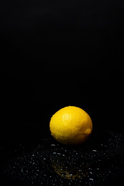 Свежий желтый лимон на черном