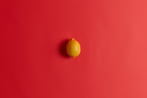 Fresh yellow sour lemon rich in vitamin c, folate, fiber and potassium to strengthen your immunity, cure cold or flu. succulent juicy tropical citrus fruit isolated isolated on red background.