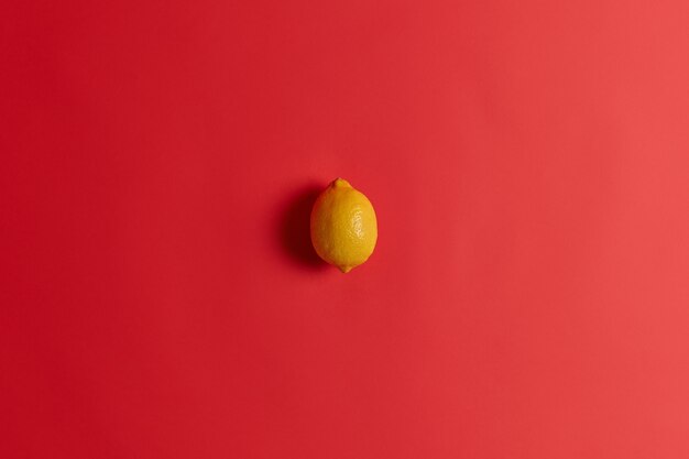 Fresh yellow sour lemon rich in vitamin C, folate, fiber and potassium to strengthen your immunity, cure cold or flu. Succulent juicy tropical citrus fruit isolated isolated on red background.