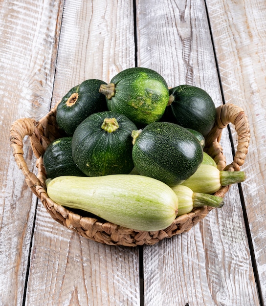 Free photo fresh zucchinis in a basket on a light wooden table