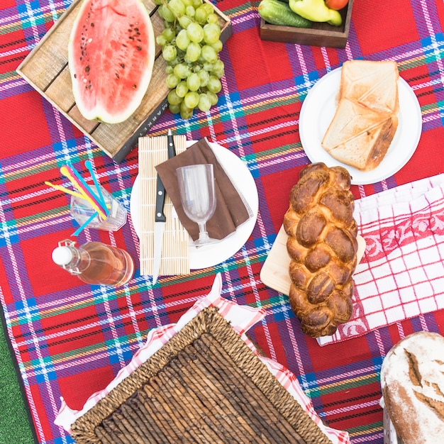 Freshly baked braided bread loaf; fruits and bread on checkered tablecloth