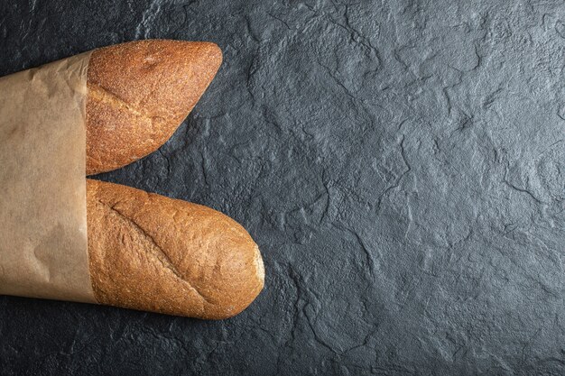 Freshly baked British baton loaf bread on black background.