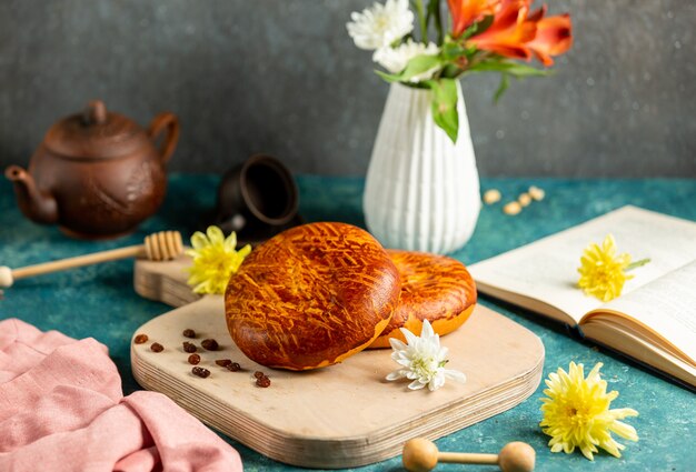 Freshly baked buns lying on the cutting board, open book and yellow flowers