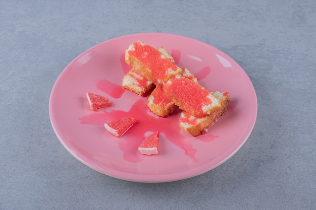 Свежеиспеченный торт и дольки грейпфрута на розовой тарелке