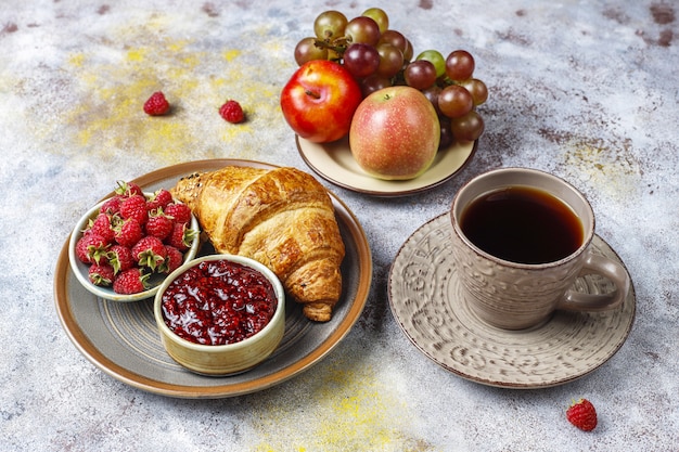 Freshly baked croissants with raspberry jam and raspberry fruits.