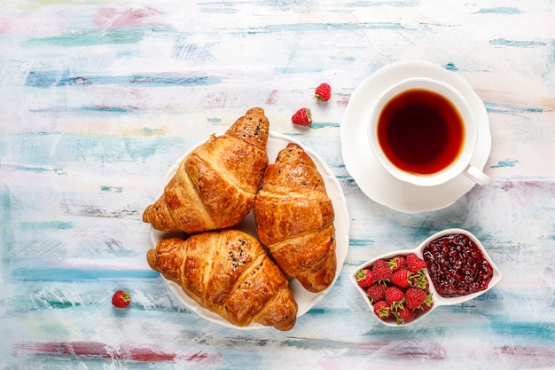 Freshly baked croissants with raspberry jam and raspberry fruits.