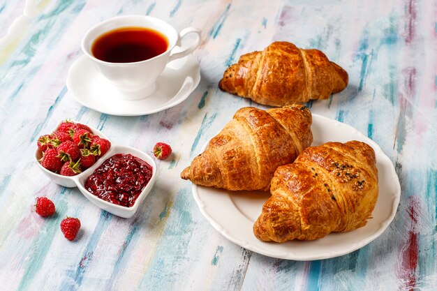 Freshly baked croissants with raspberry jam and raspberry fruits.