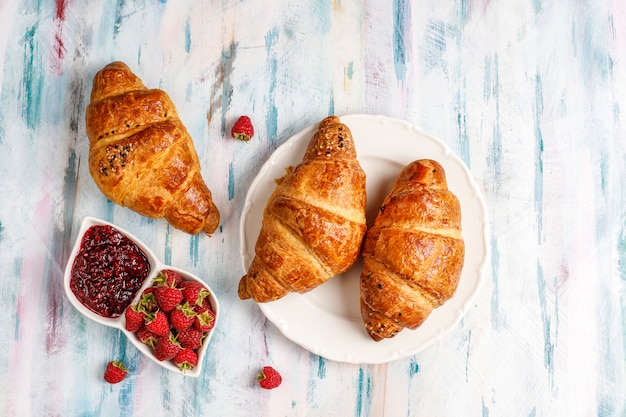 Freshly baked croissants with raspberry jam and raspberry fruits.