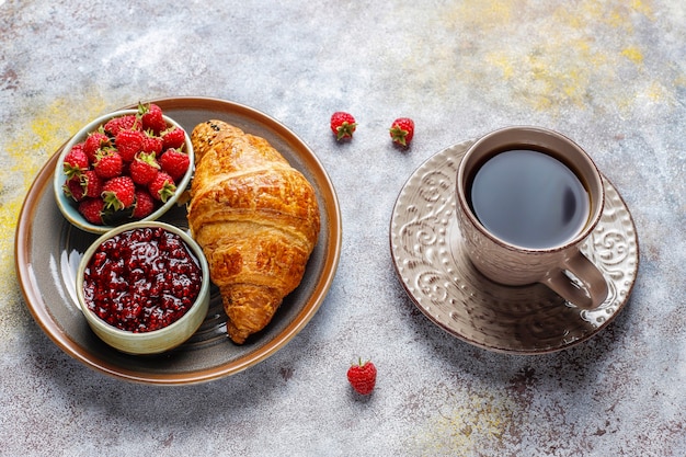 Freshly baked croissants with raspberry jam and raspberry fruits.