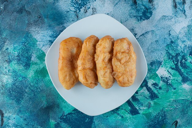 Freshly baked fried dough stick on plate, on the marble table. 