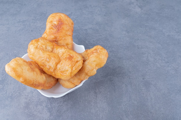 Freshly baked fried dough stick on plate, on the marble.